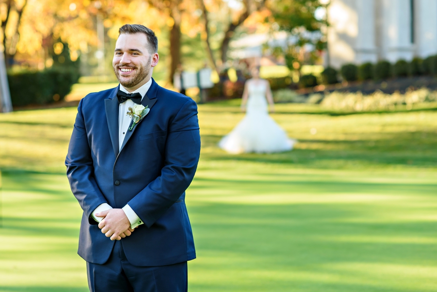 A groom waiting while his bride walks up behind him for their first look.